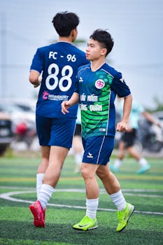 Two young football players in action on a turf field in Hanoi, Vietnam.