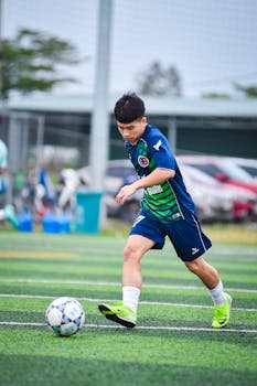 A young soccer player intensely focused during a match on an artificial turf field.
