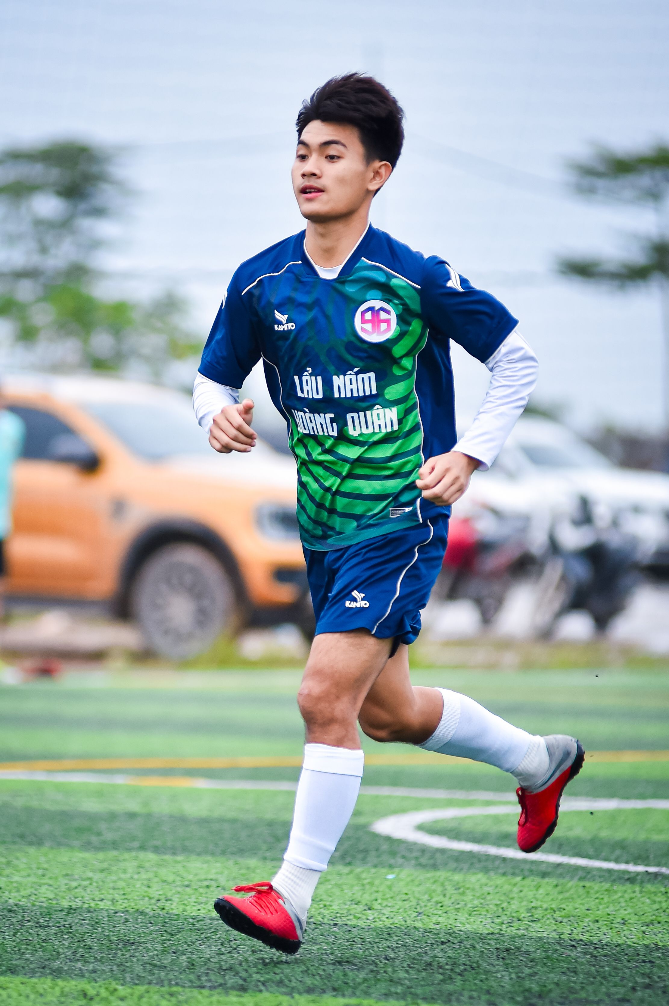 A young football player in motion on a turf field in Hanoi, Vietnam.