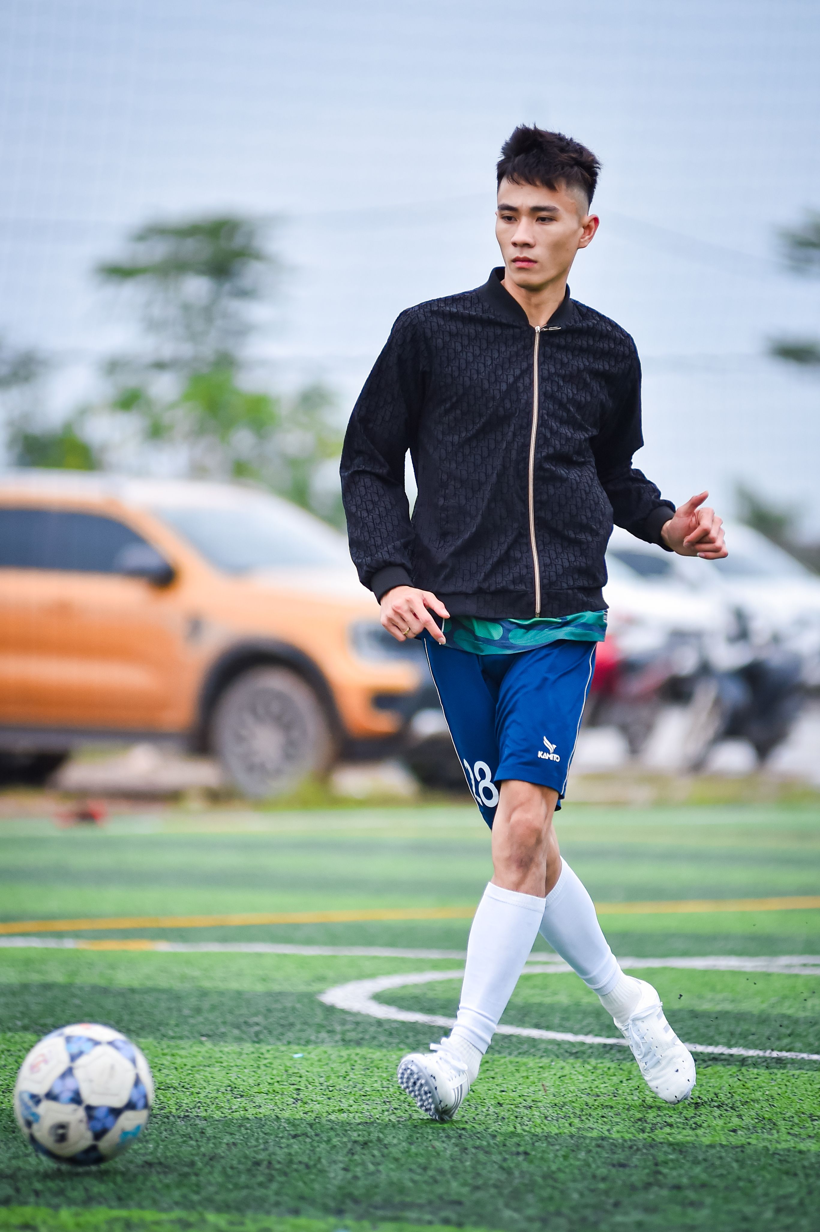 Dynamic capture of a young football player on an artificial turf field in Hà Nội, Việt Nam.