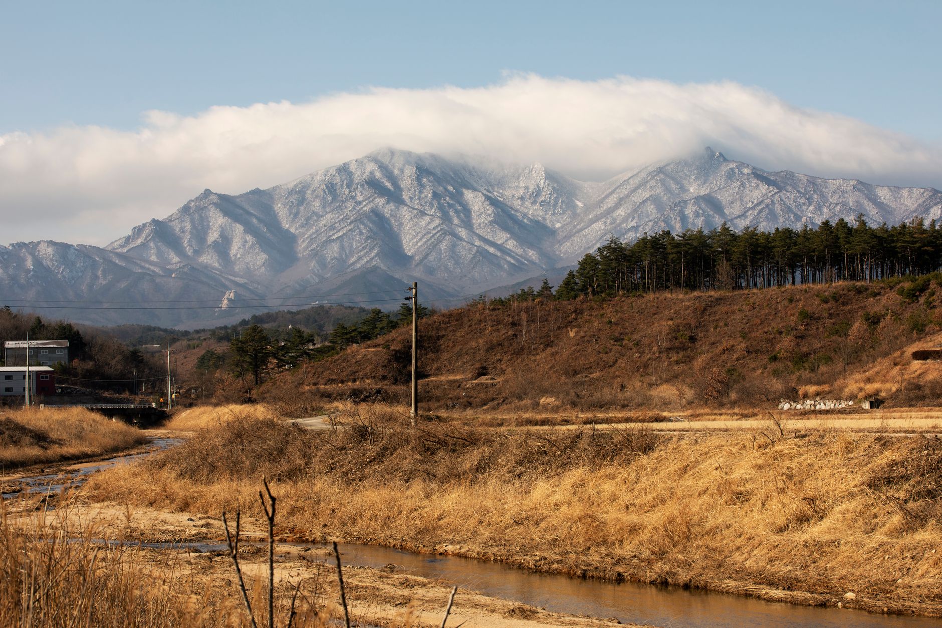 Scenic view of Seoraksan Mountain covered in snow with a clear river in foreground.