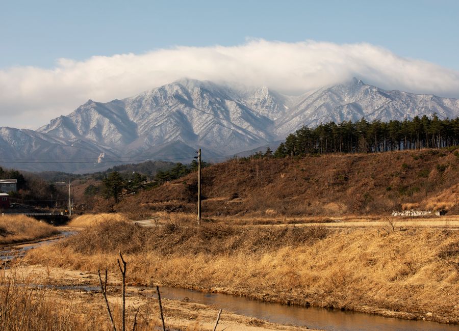 Scenic view of Seoraksan Mountain covered in snow with a clear river in foreground.