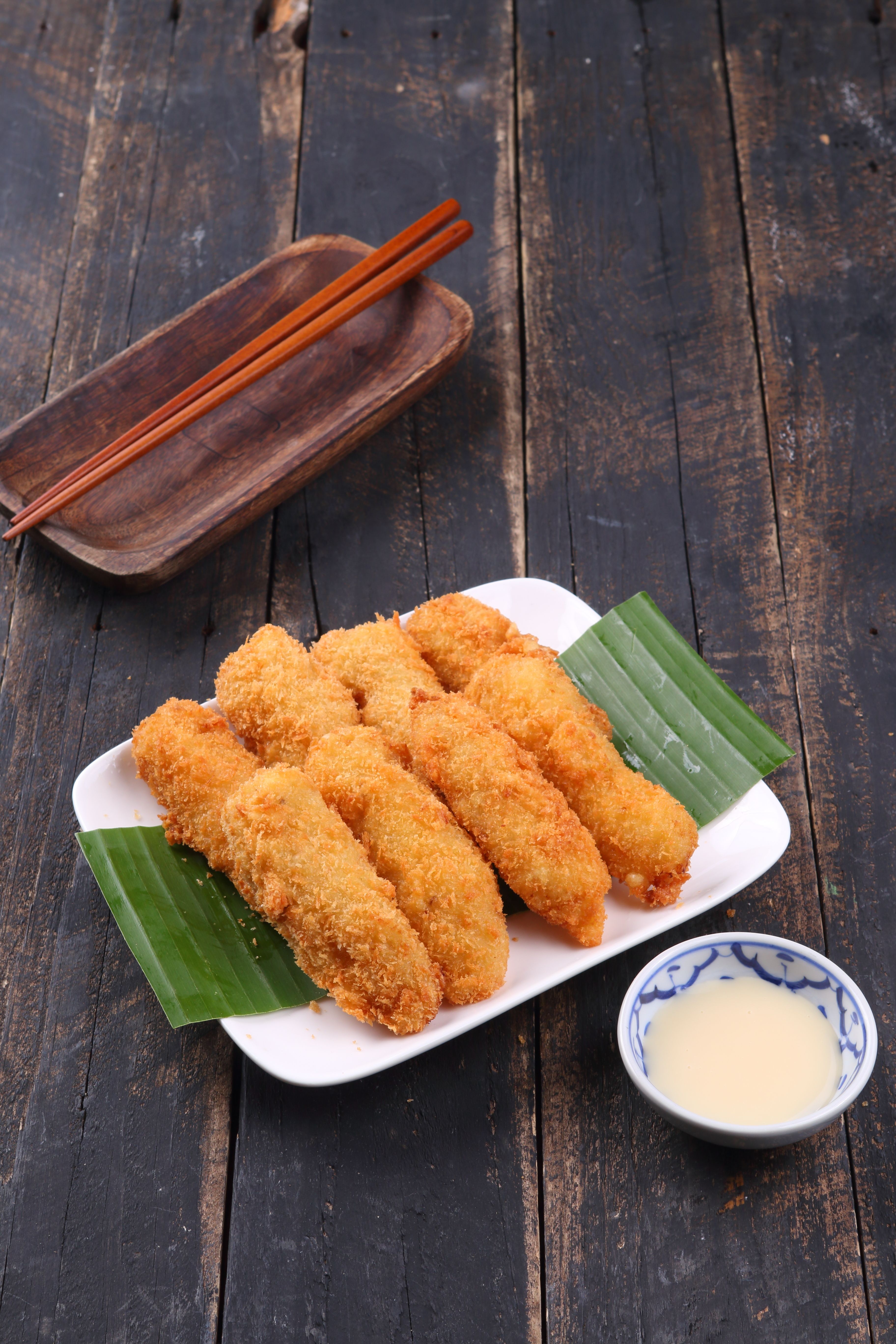 Delicious fried bananas served on a white plate with sauce, perfect for sweet tooth cravings.
