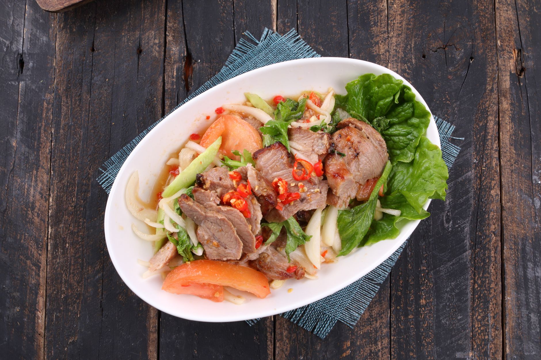 Sliced brisket layered on a bed of fresh salad greens