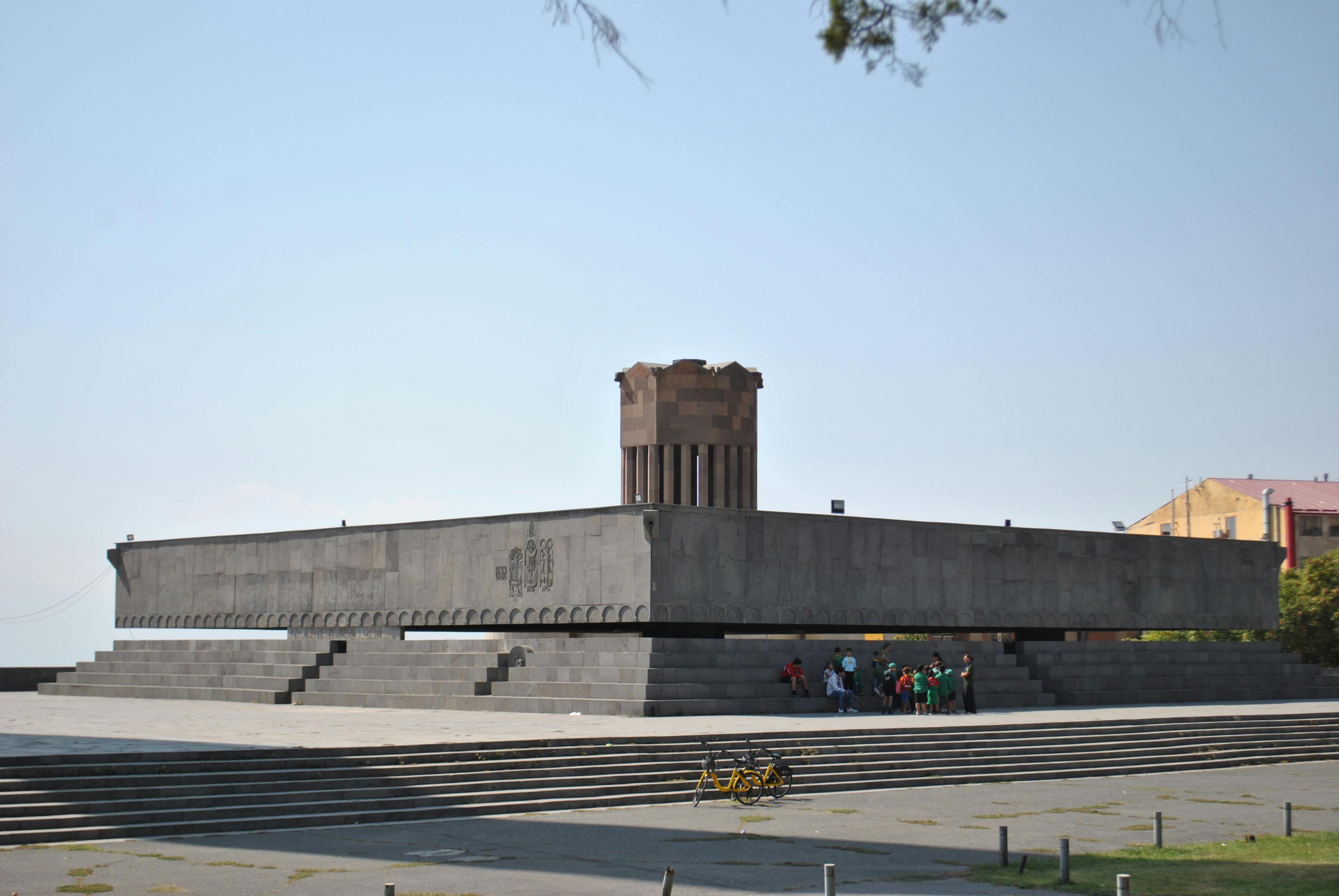 A large monument in Yerevan surrounded by visitors on a sunny day.