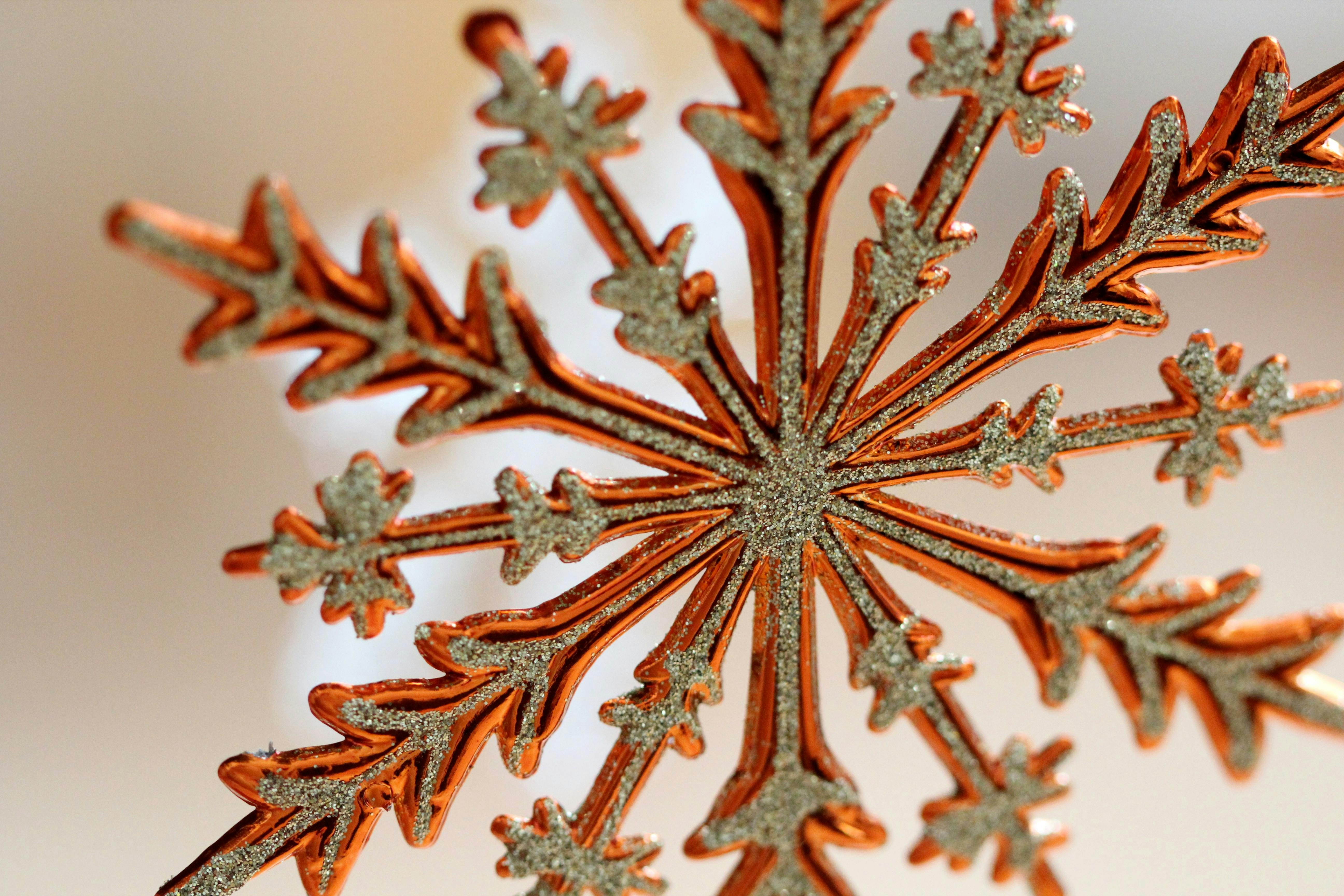Detailed close-up shot of an orange snowflake ornament with a festive, wintery feel.