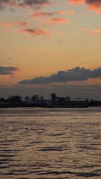 A tranquil sunset scene over a waterfront with soft clouds and reflections.