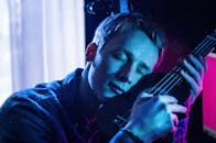 一名男子拥抱尤克里里琴的特写，在霓虹灯光下营造出喜怒无常的氛围