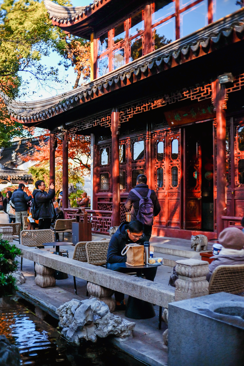 Free Visitors enjoy a sunny day in a tranquil traditional Chinese garden courtyard. Stock Photo