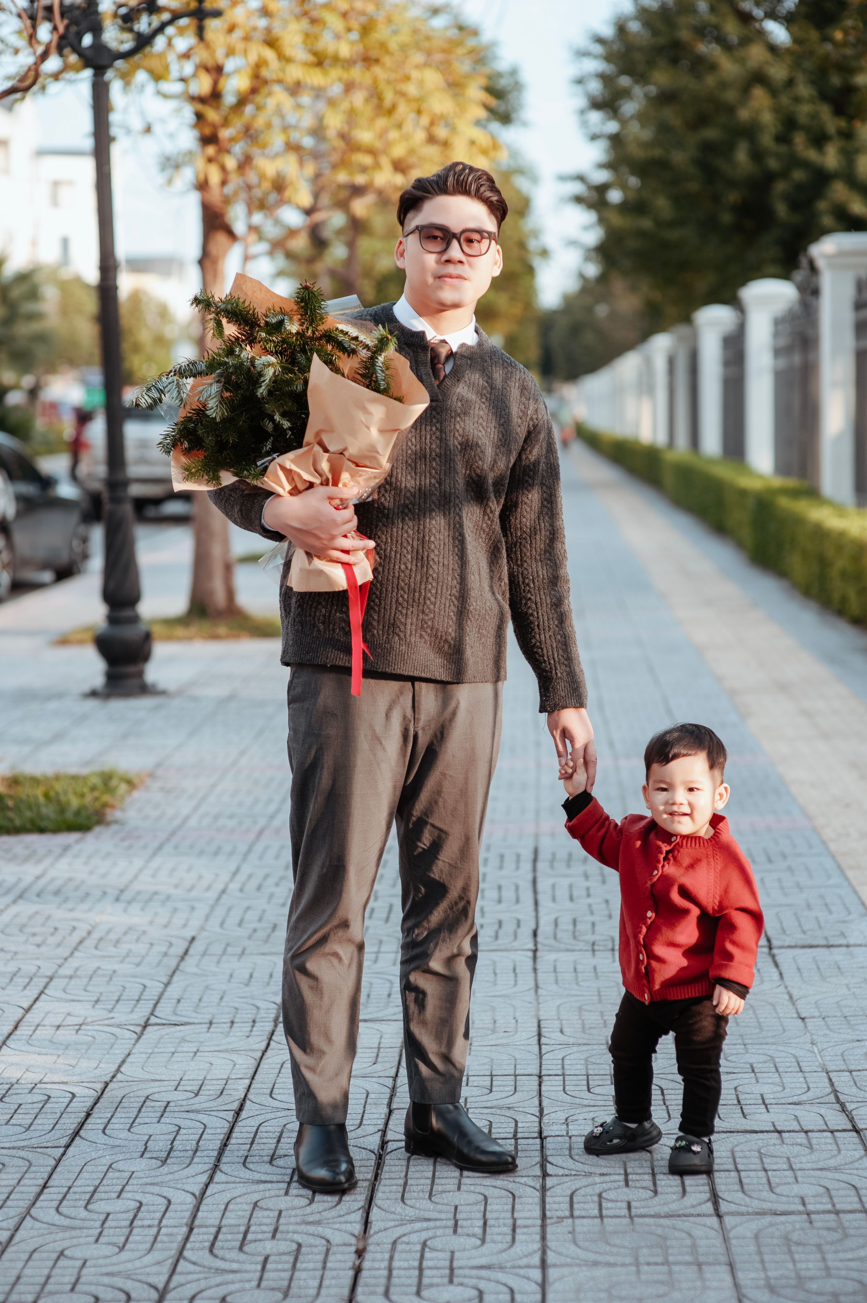 father and son walking with flowers on sunny day