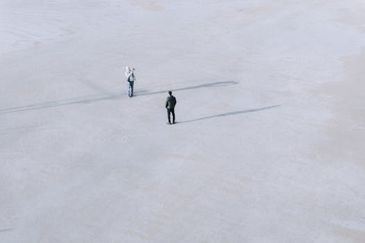 Two individuals on a vast, empty salt flat in İstanbul, Türkiye, casting long shadows in a minimalist landscape.