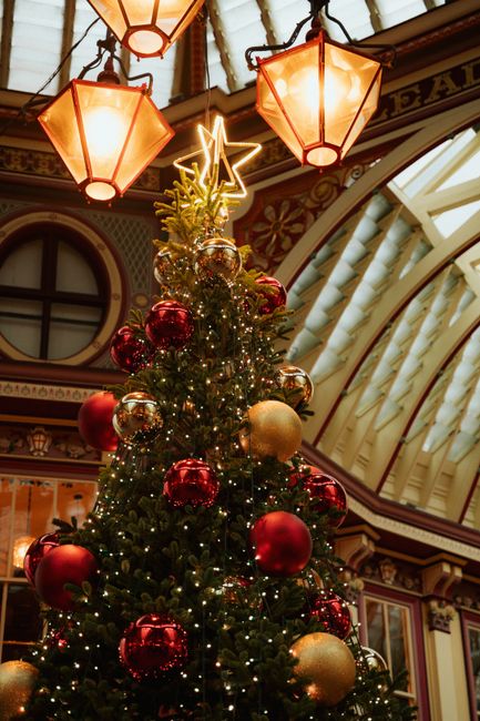 Elegant Christmas tree with ornaments inside a vintage-style shopping arcade.
