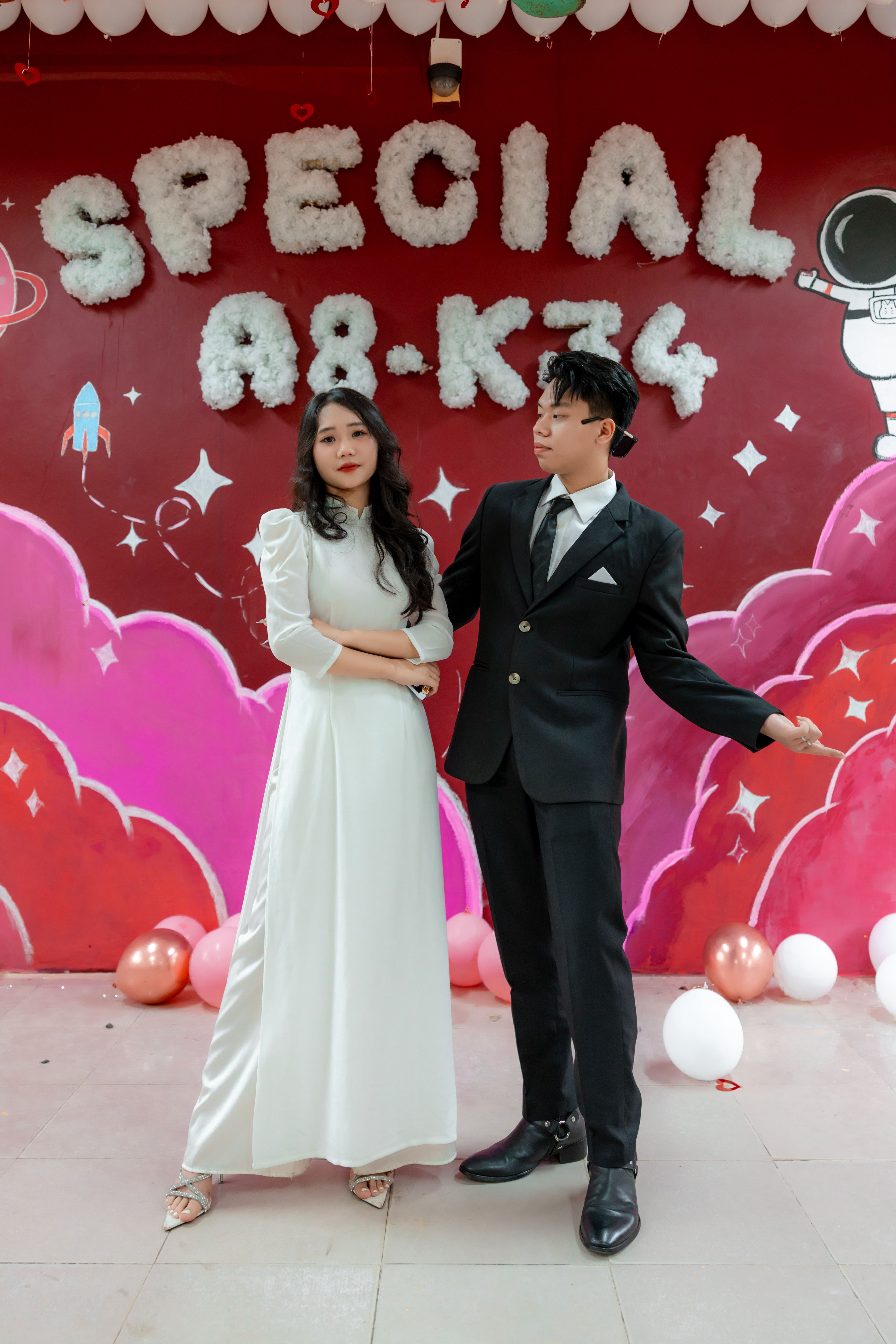 Couple in formal attire posing in front of a cosmic-themed backdrop at a special event.