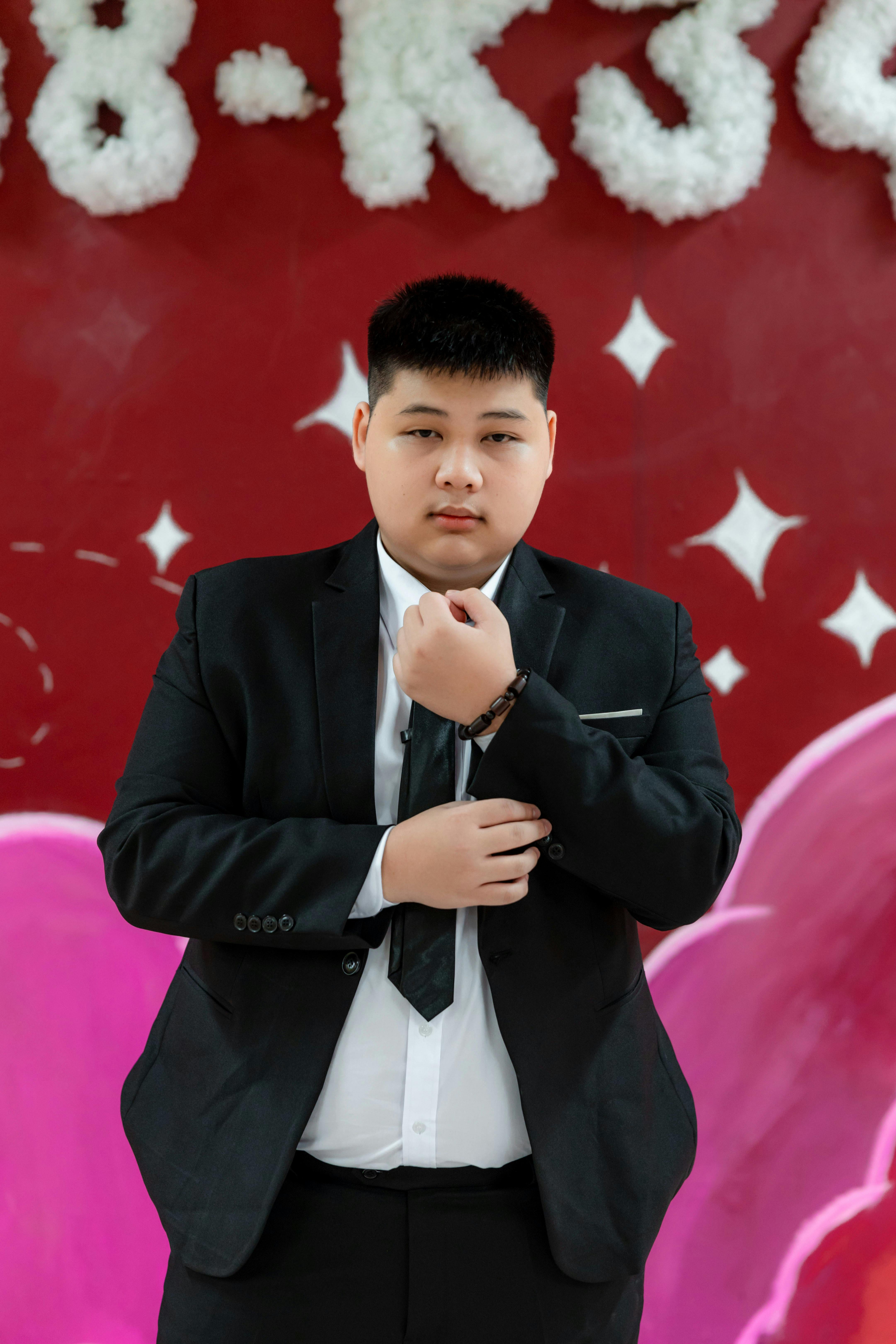 무료 정장을 입은 자신감 넘치는 젊은 남성이 생동감 넘치는 장식 배경 앞에서 포즈를 취하고 있다. 스톡 사진