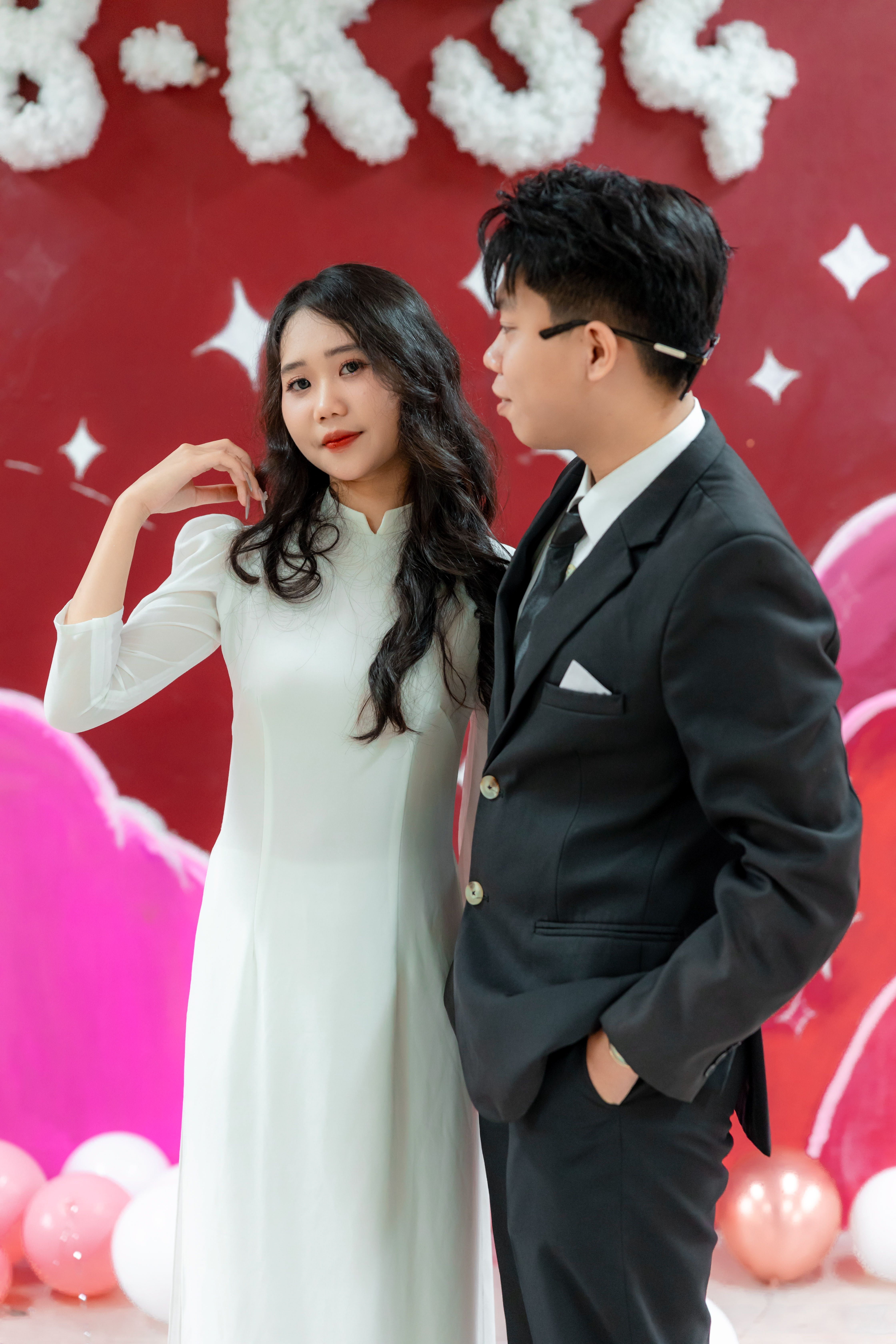Sophisticated couple in formal attire posing against a vibrant backdrop, exuding elegance and style.