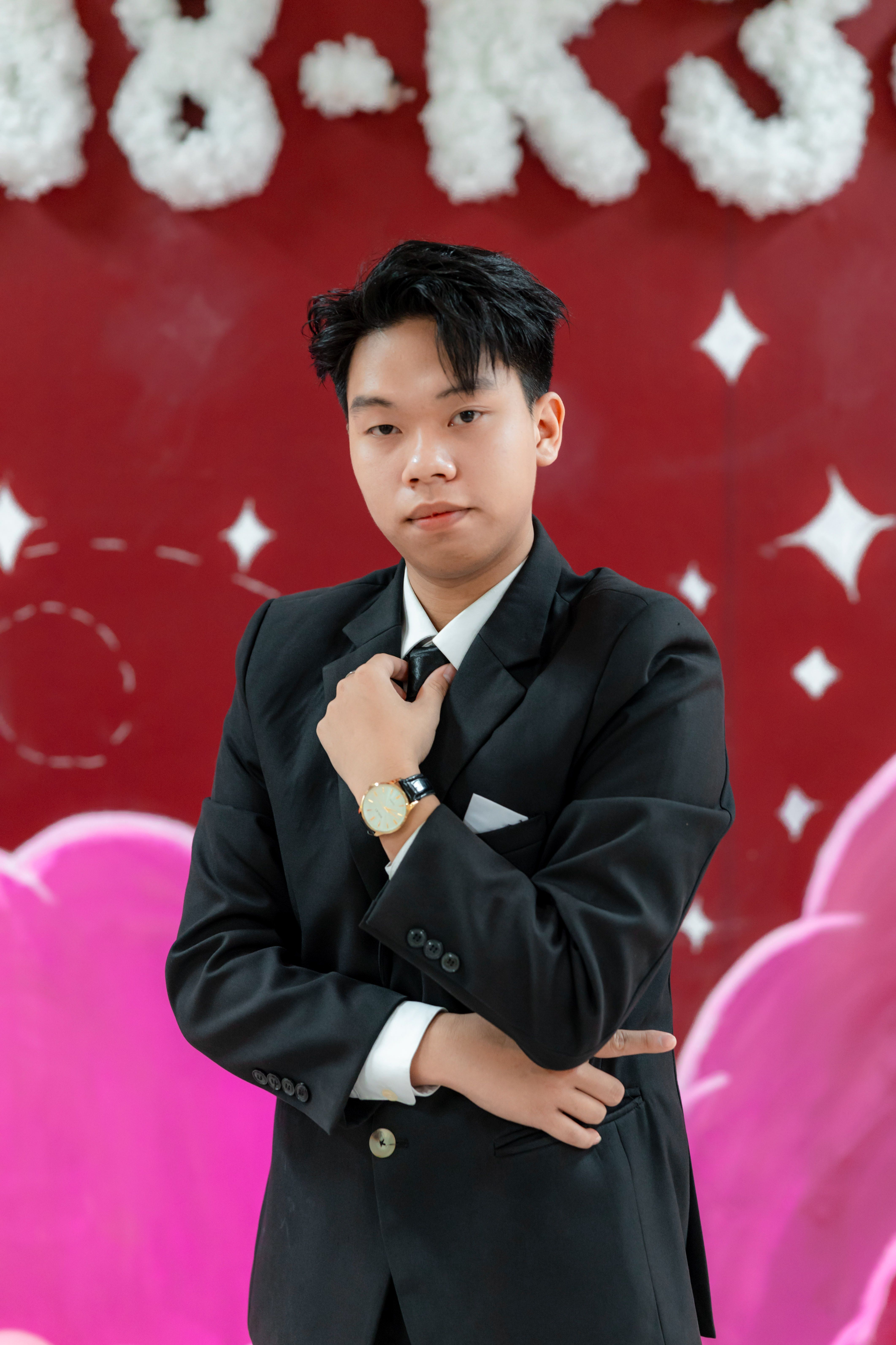 Confident young man in a suit posing against a vibrant, artistic background indoors.