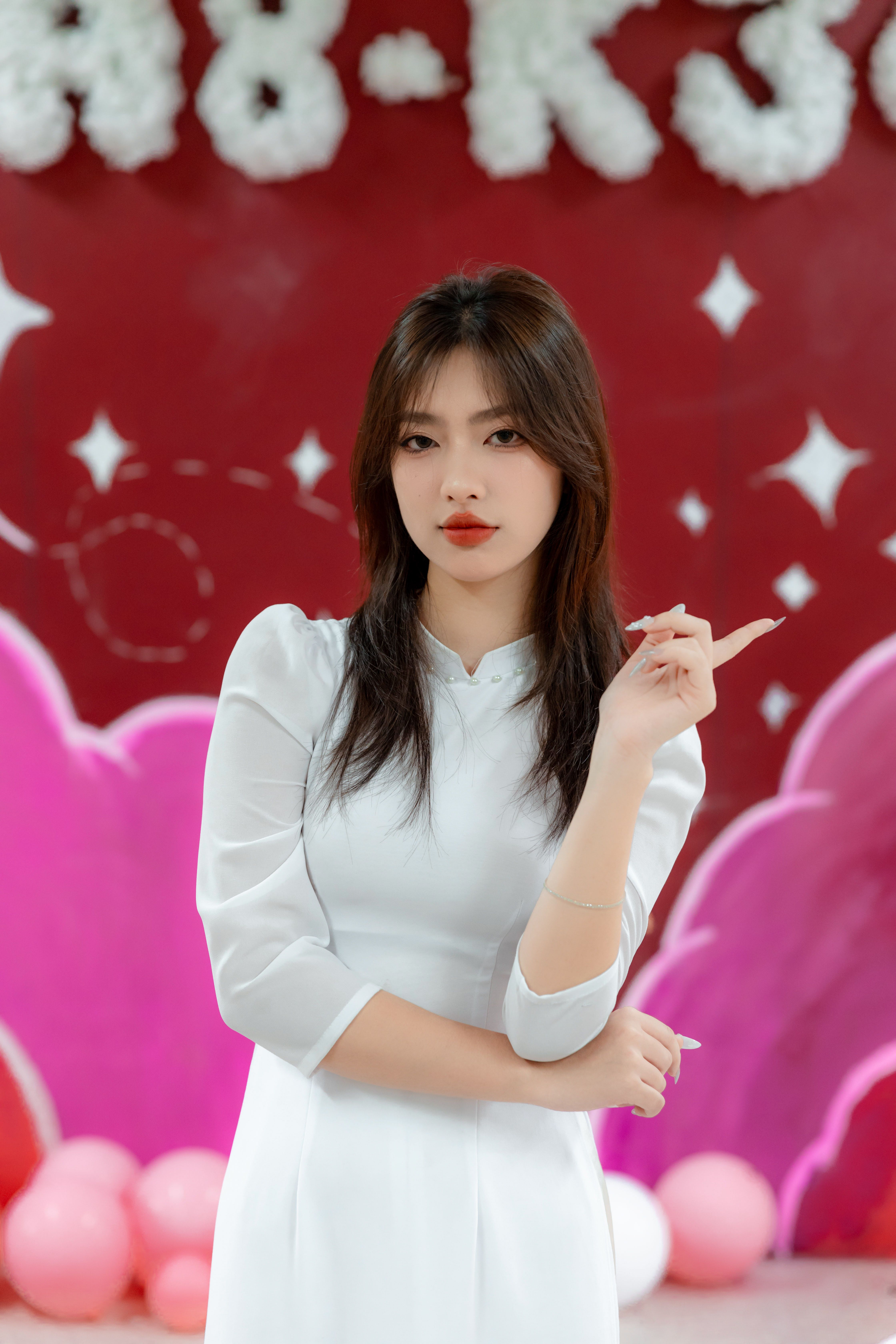 Portrait of a woman in a white dress against a colorful background indoors.