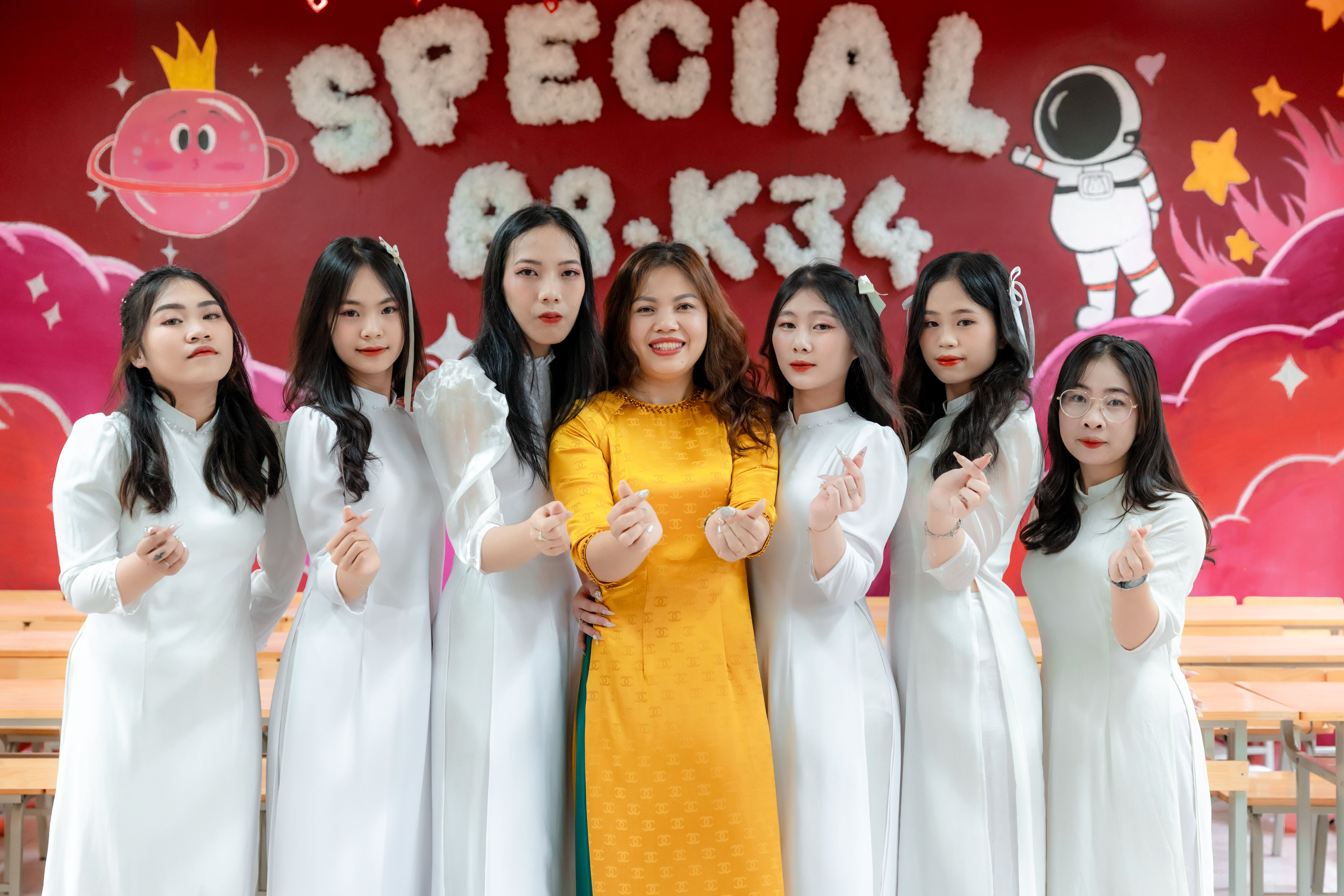 Happy women in traditional dresses posing with hand gestures in colorful indoor setting.