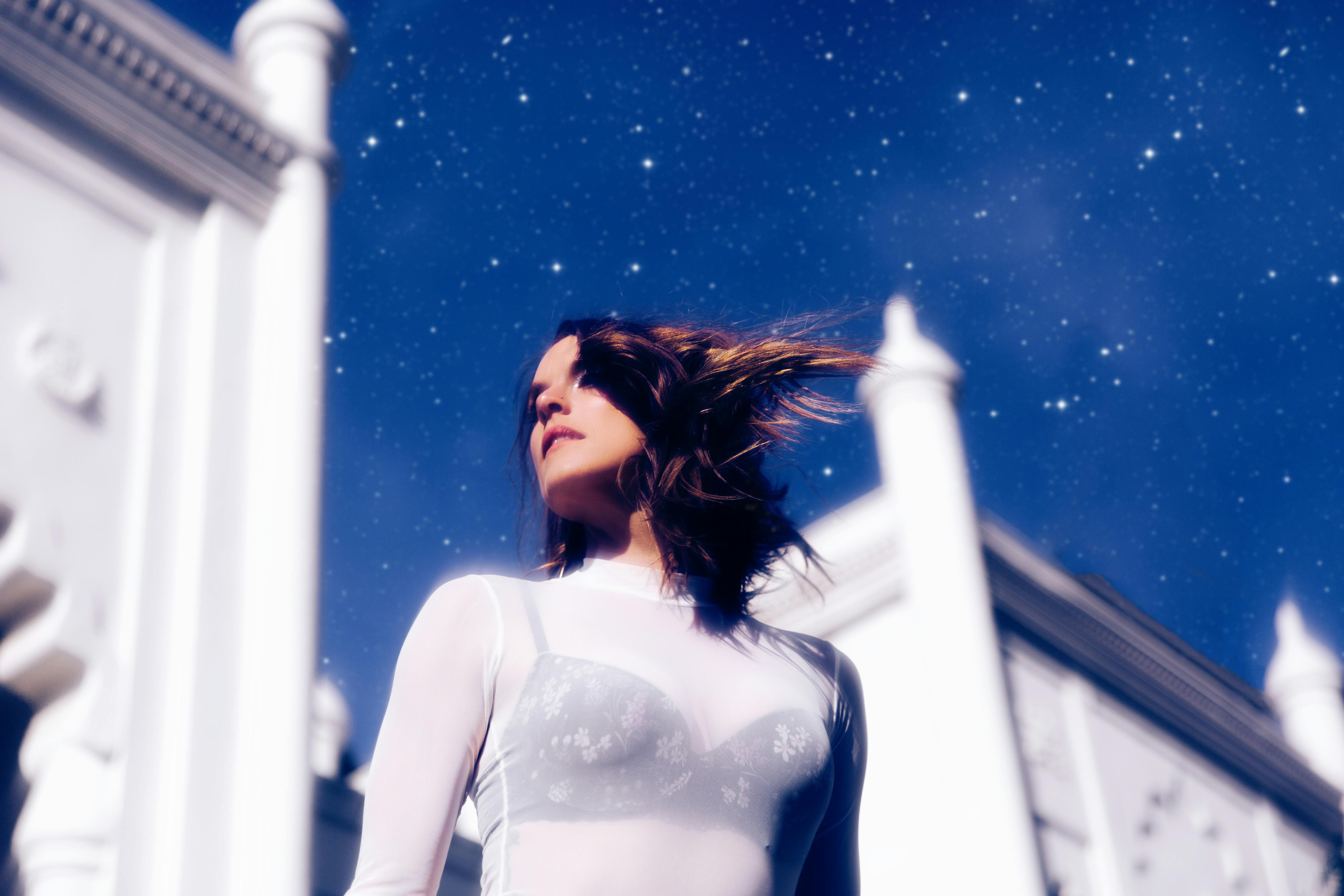 Low angle shot of a woman under a starry sky in Los Angeles, exuding elegance and mystery.