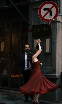 A couple elegantly dances on a city street by a 'no left turn' sign, capturing a romantic moment.