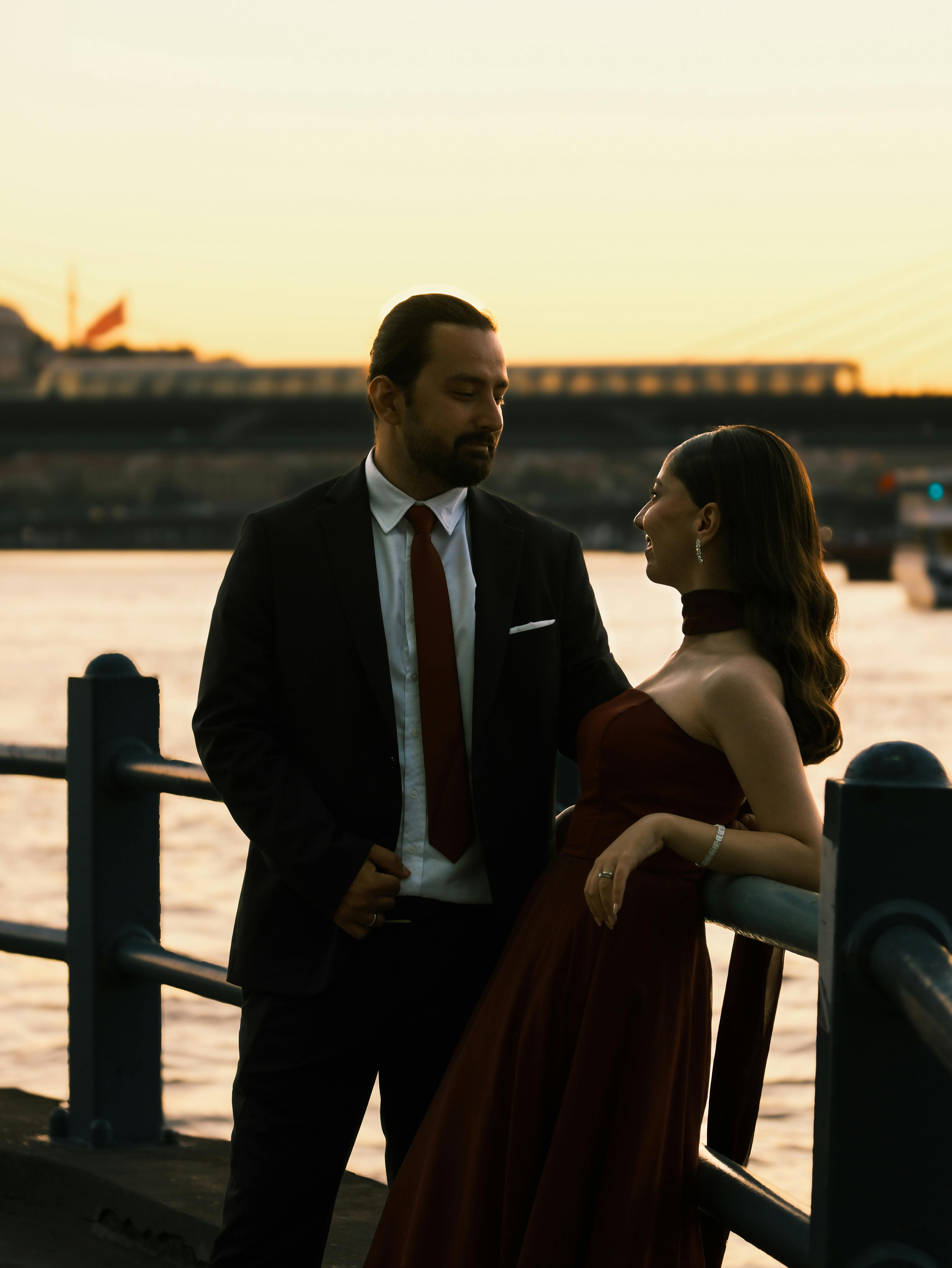 Elegant couple posing by the water at sunset, exuding romance.