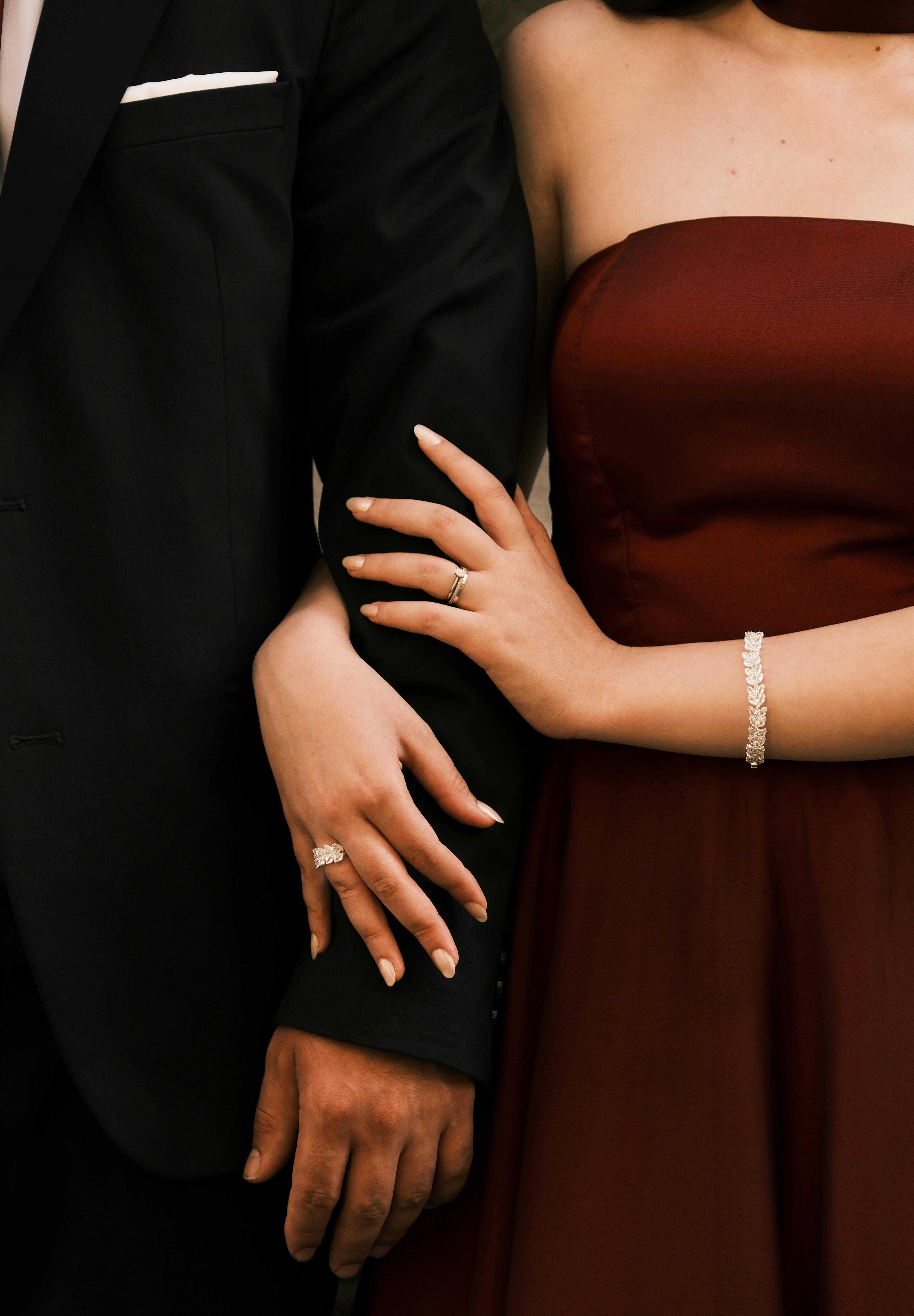 Closeup of an elegantly dressed couple holding hands at a formal event.