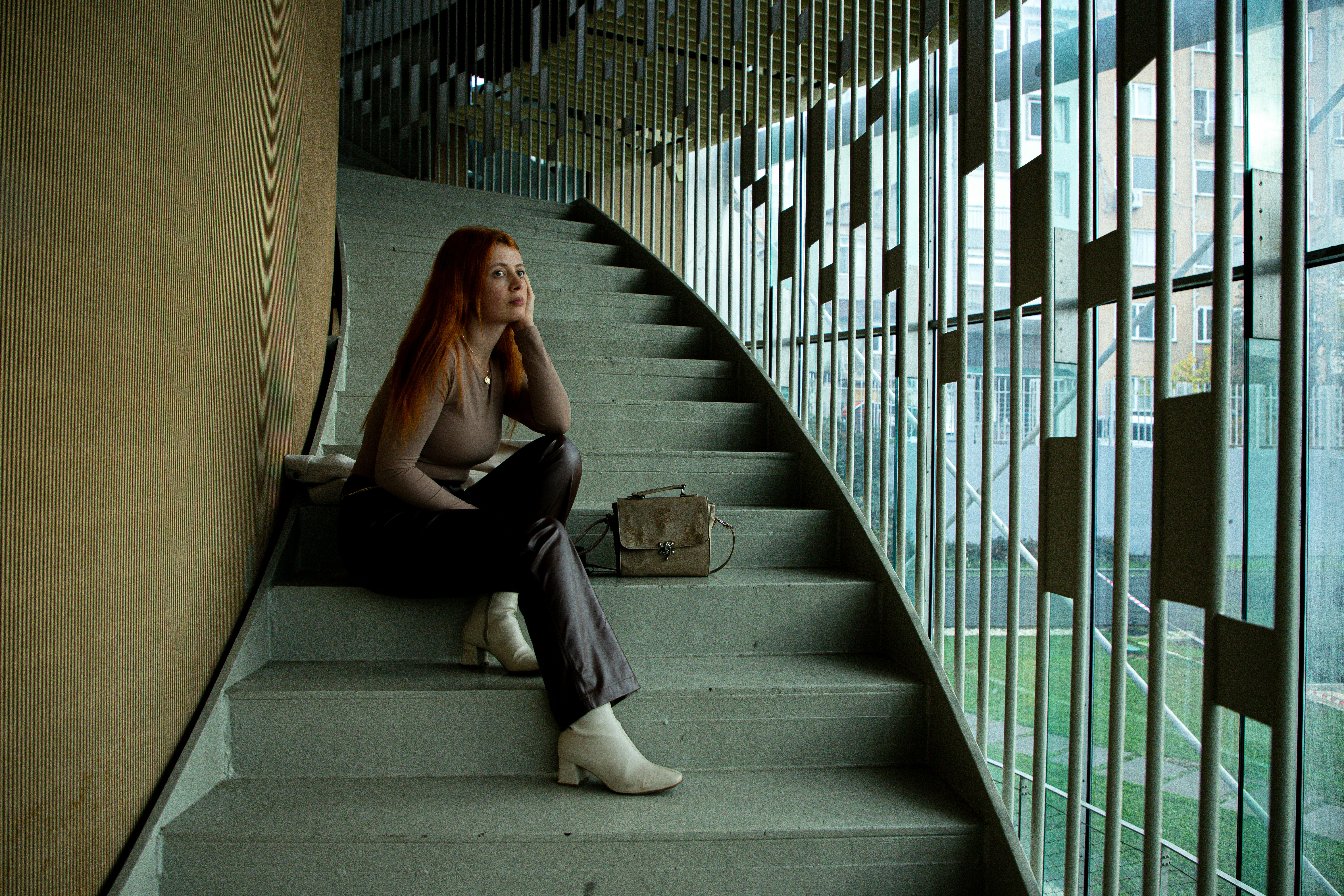 Woman with red hair on a geometric staircase, showcasing fashion in Istanbul.