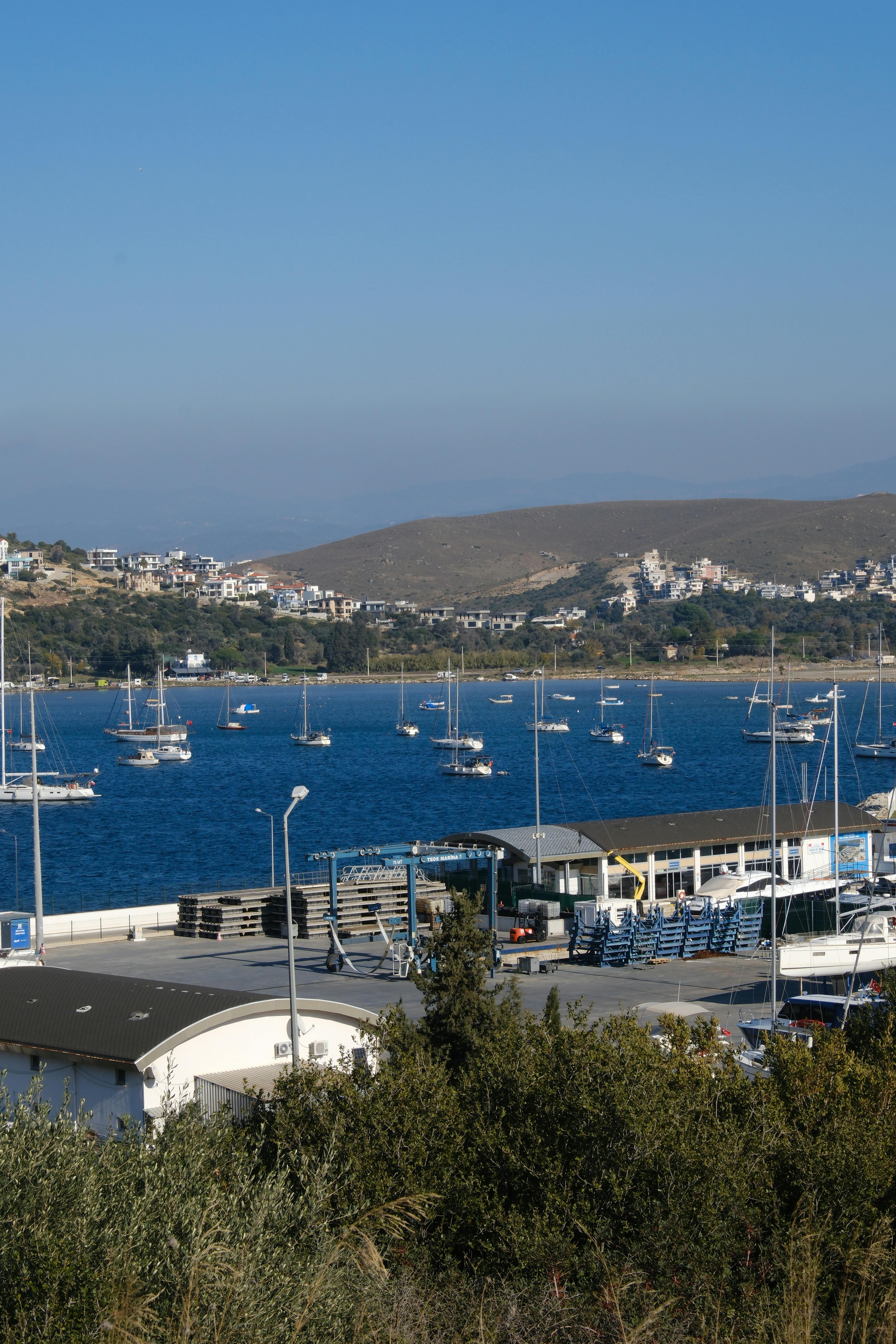 Tranquil view of a harbor with sailboats in Sığacık, İzmir, Türkiye under a clear blue sky.