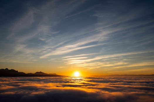 Stunning sunset view above cloud layers with mountains in Lausanne, Switzerland.