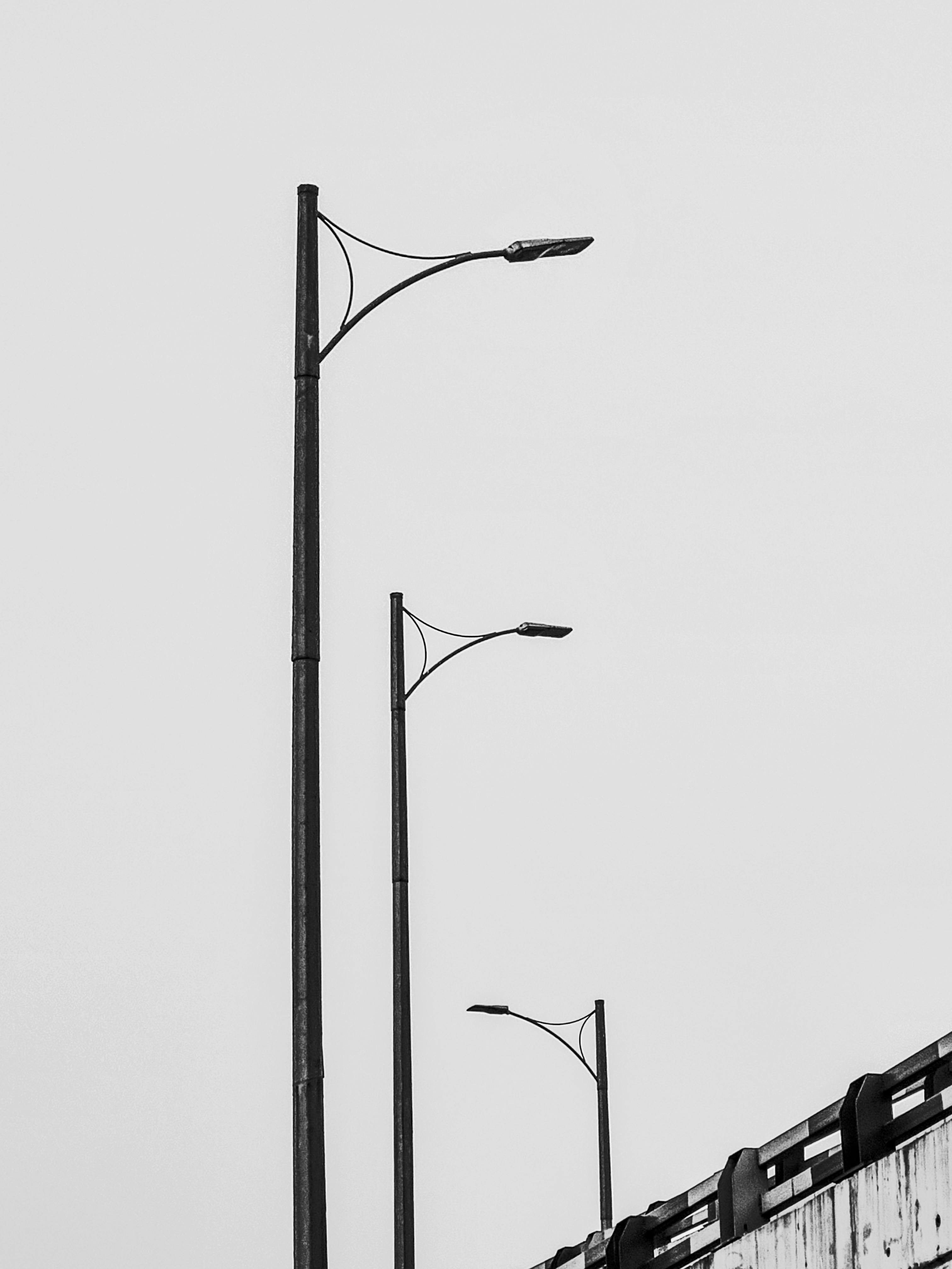 Gratis Una foto minimalista in bianco e nero di lampioni lungo un ponte. Foto a disposizione