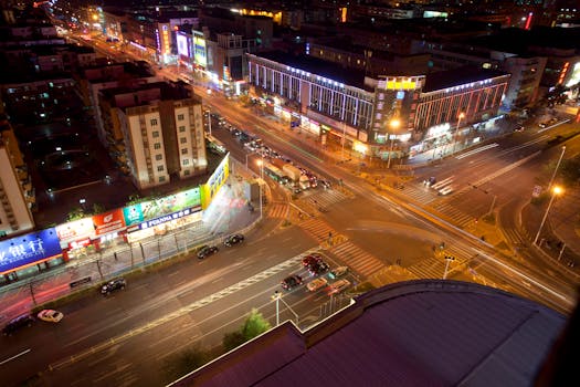 A dynamic aerial view of a bustling city at night with vibrant lights and motion blur traffic.
