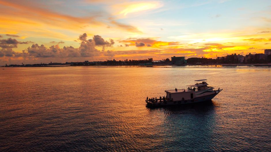 A public ferry arriving at the bustling jetty of Maafushi island in Kaafu Atoll, Maldives, with local people and tourists