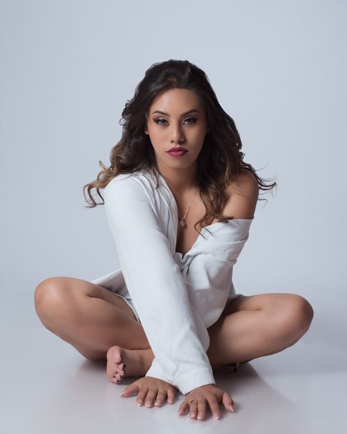 Free Artistic portrait of a woman seated in a cozy white sweater, exuding elegance and poise. Stock Photo
