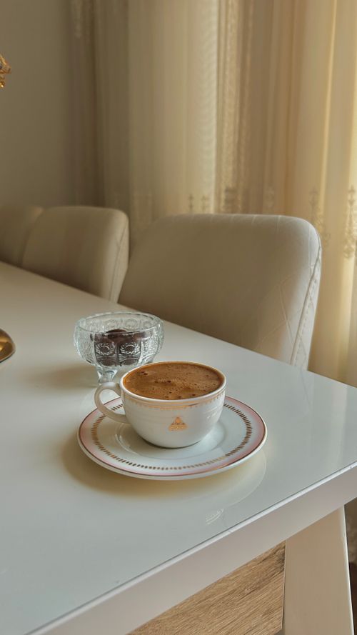 Free A stylish cup of coffee on a sleek white table with soft natural light and elegant surroundings. Stock Photo