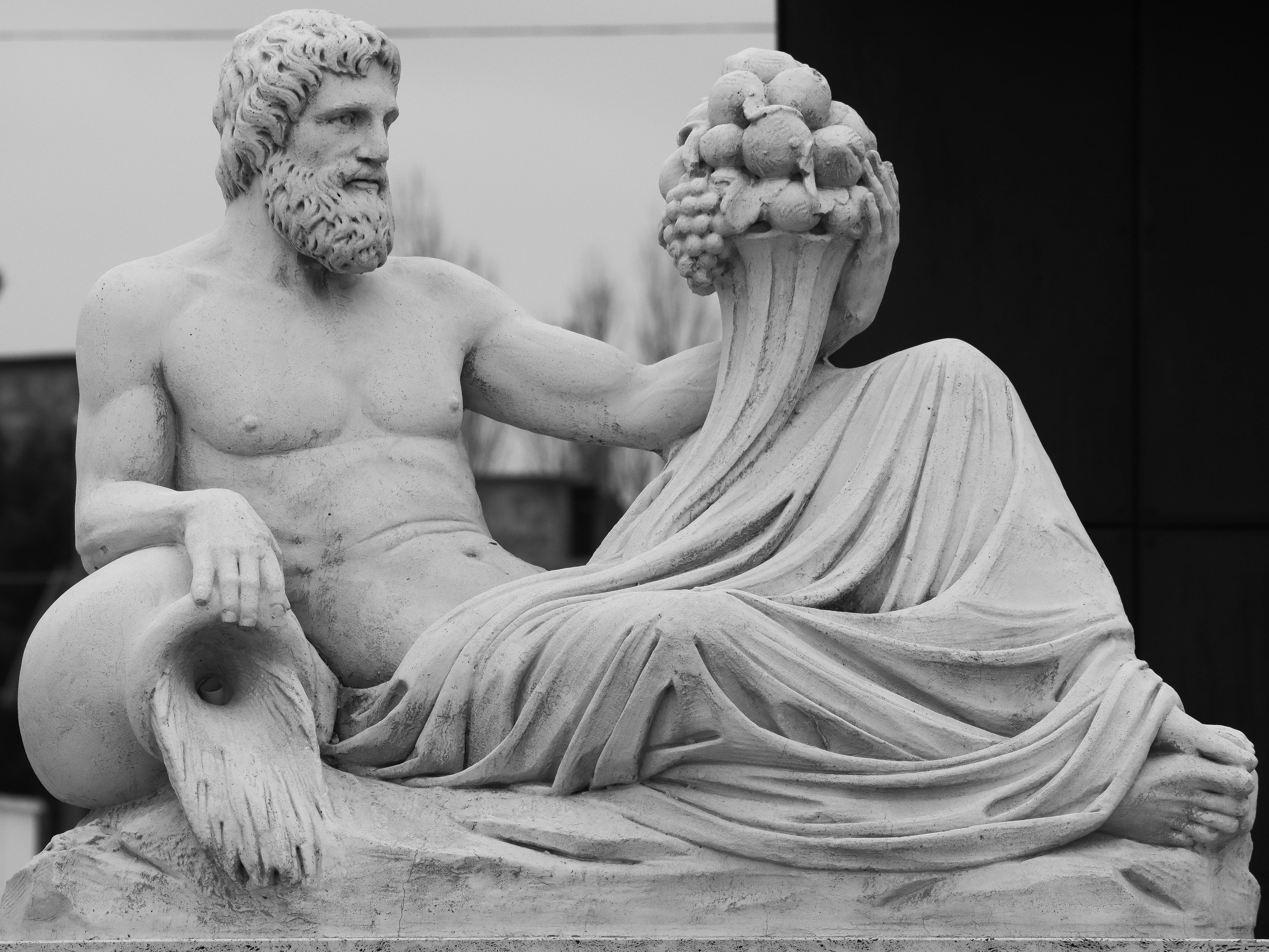 Gratuit Image en noir et blanc d'une sculpture classique en pierre représentant une figure allongée tenant une corne d'abondance. Photos