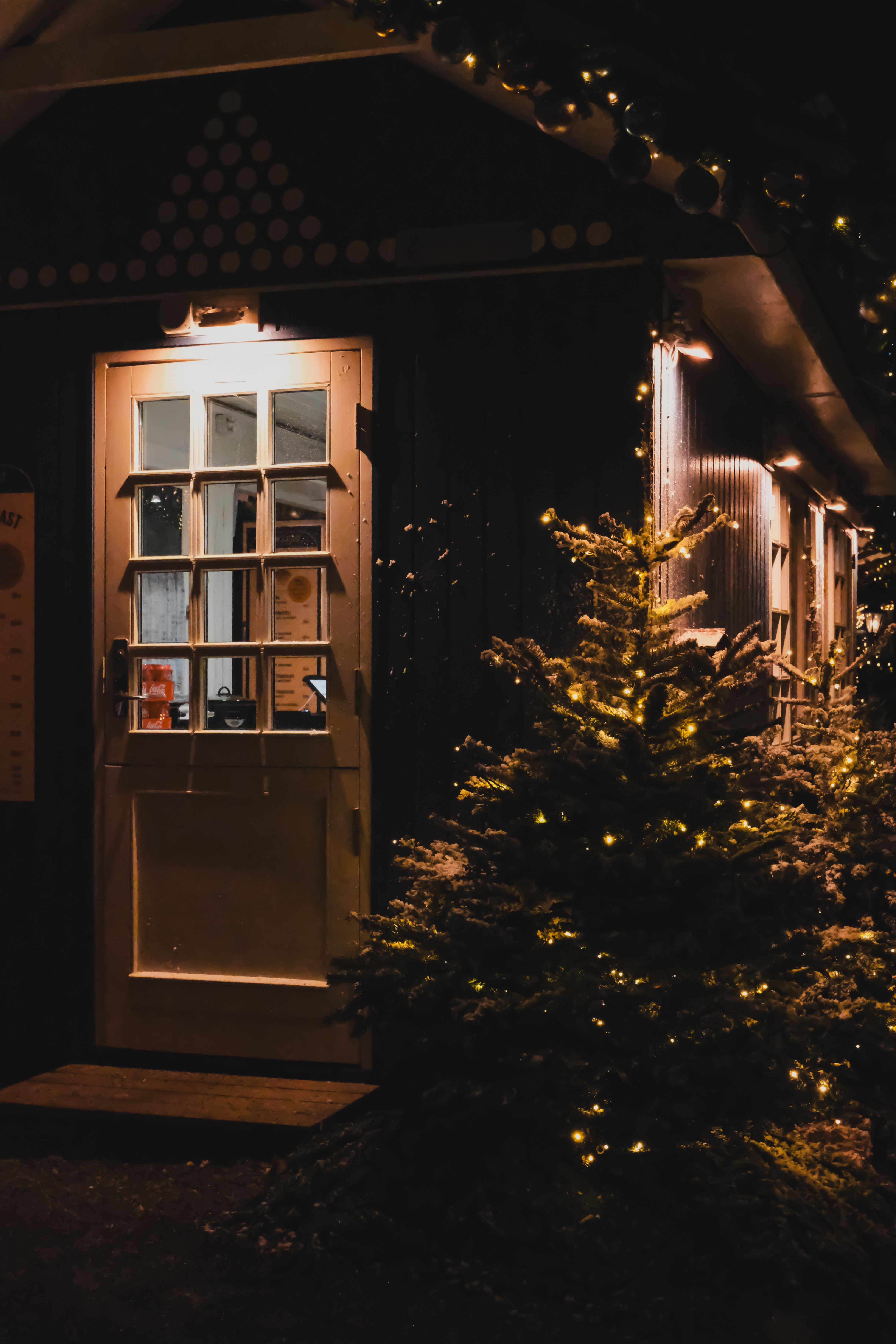 A beautifully lit Christmas tree outside a warm, inviting doorway at night in Copenhagen.