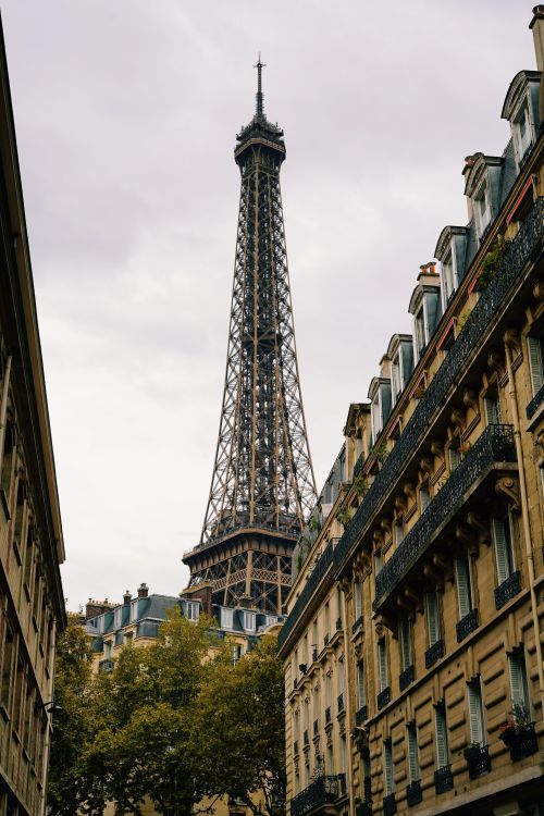 Free Eiffel Tower seen between classic Parisian buildings, a perfect architectural framing in autumn. Stock Photo