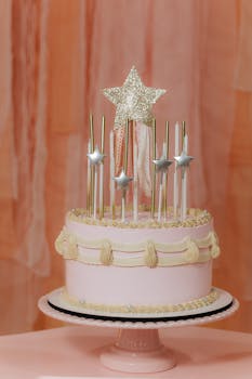 Beautiful pink birthday cake adorned with star candles and a glittering topper.
