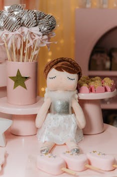 Charming pink themed birthday setup with toy doll, cake pops, and sweets.