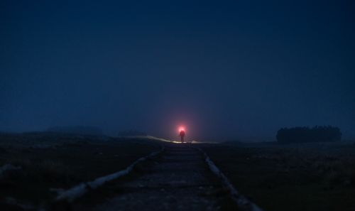 Free A person with a flashlight walking on a foggy path at night, creating an eerie and adventurous atmosphere. Stock Photo