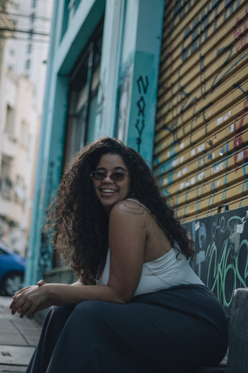Free Portrait of a smiling woman sitting on a city street with graffiti walls. Stock Photo