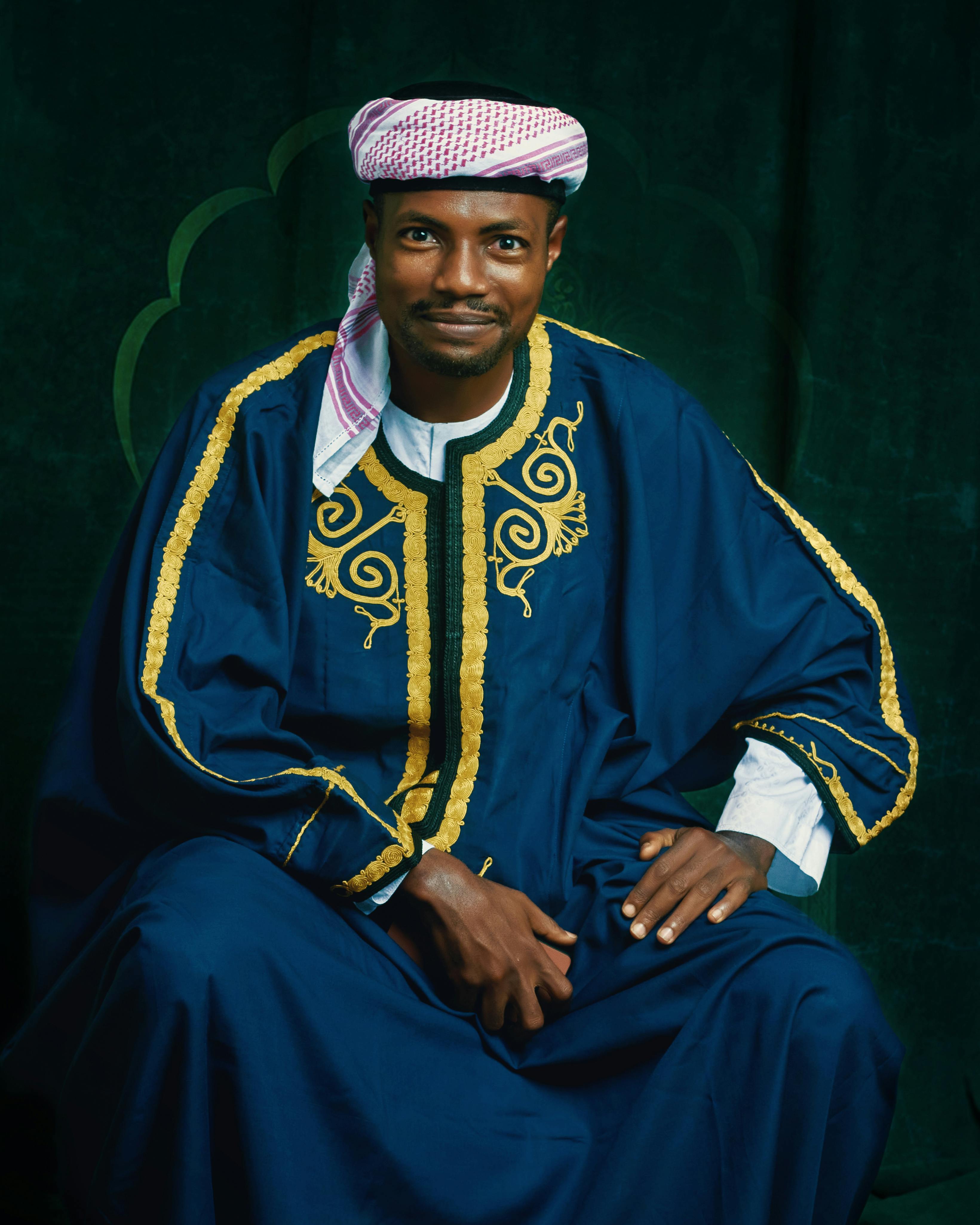 A man in traditional Middle Eastern clothing with intricate patterns, posing for a portrait.