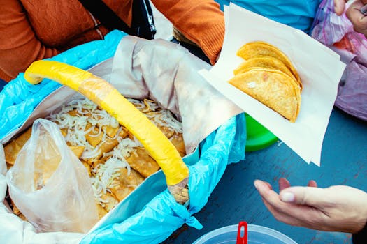 Street vendor displaying handmade tacos with onions in a vibrant setup.