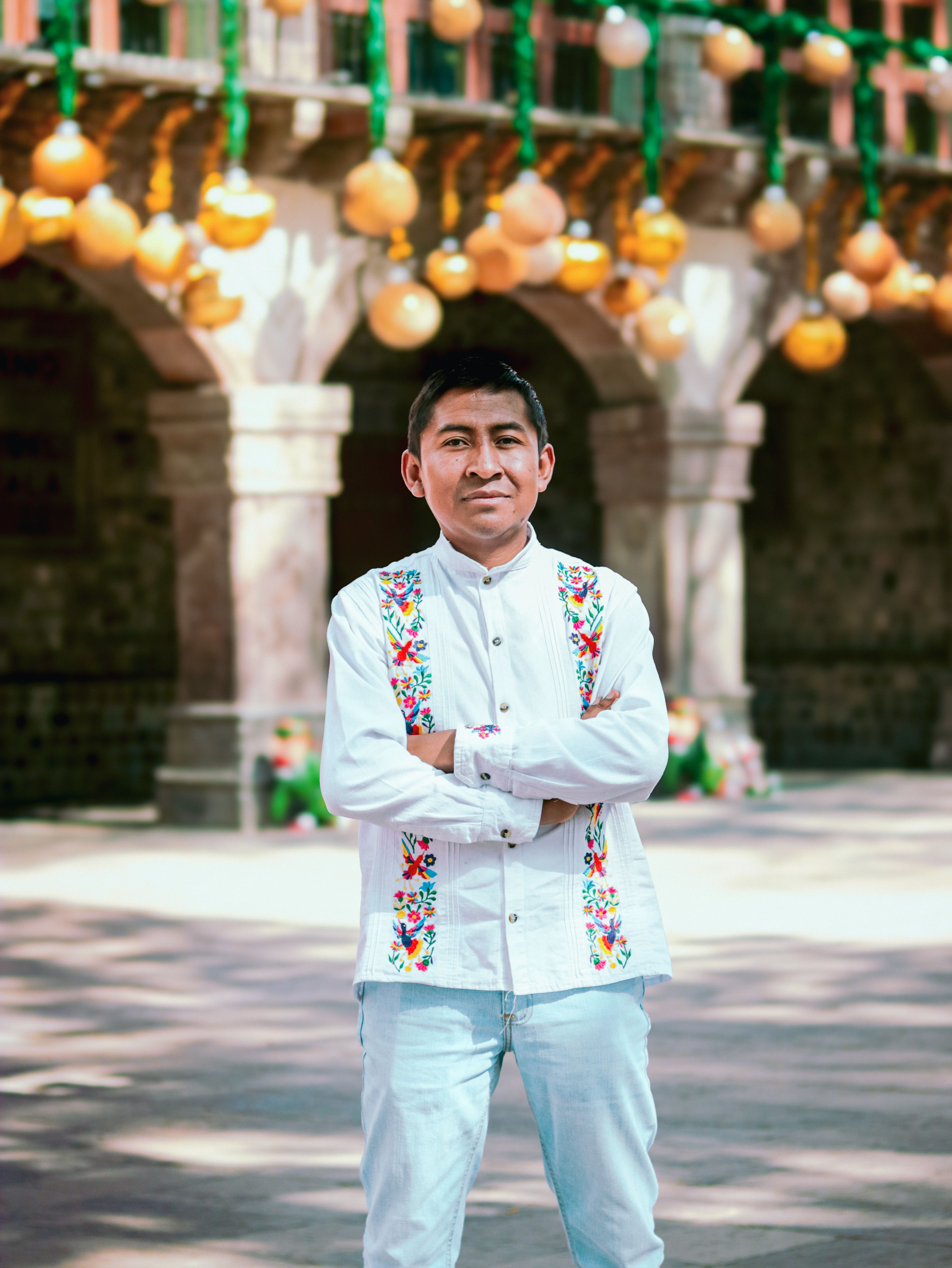Portrait of a man in traditional attire with festive decorations in the background, captured in an outdoor setting.