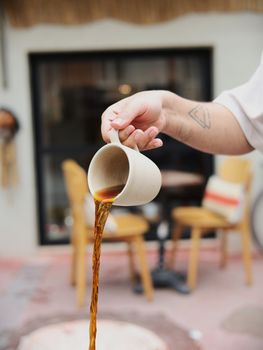 Artistic coffee pour captured at an outdoor cafe, highlighting detail and movement.