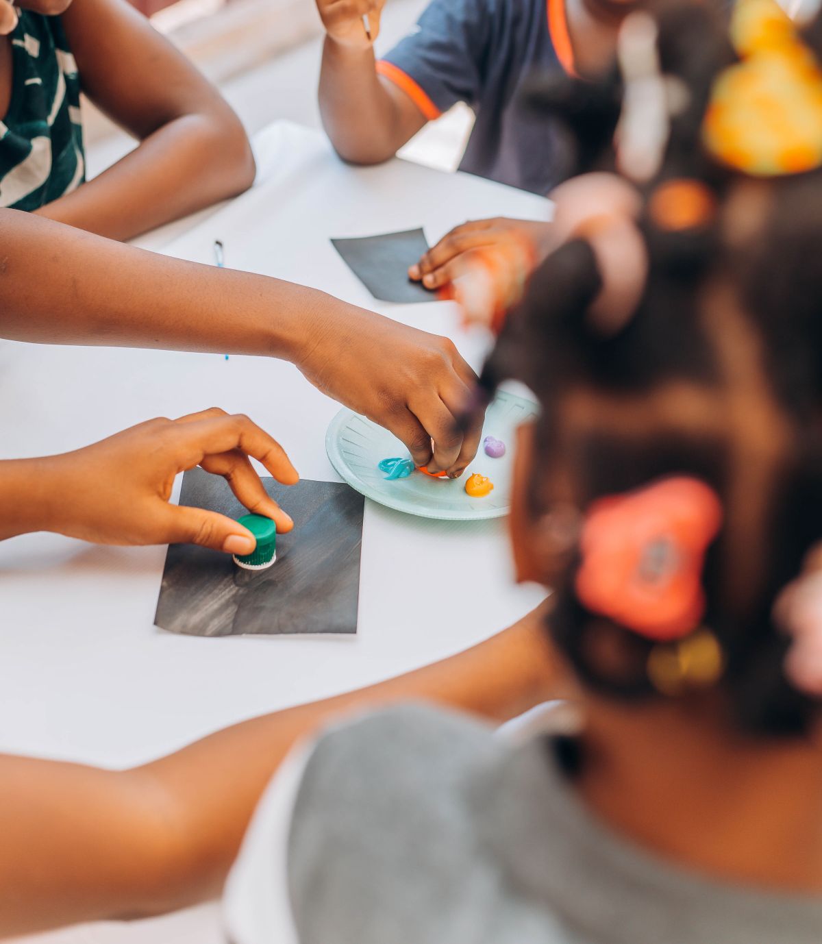 Children painting together at a table with brushes and bright watercolors