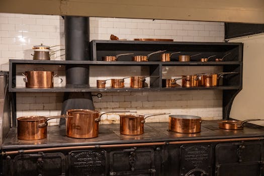 A collection of copper cookware on an old-fashioned stove in a classic kitchen setting.