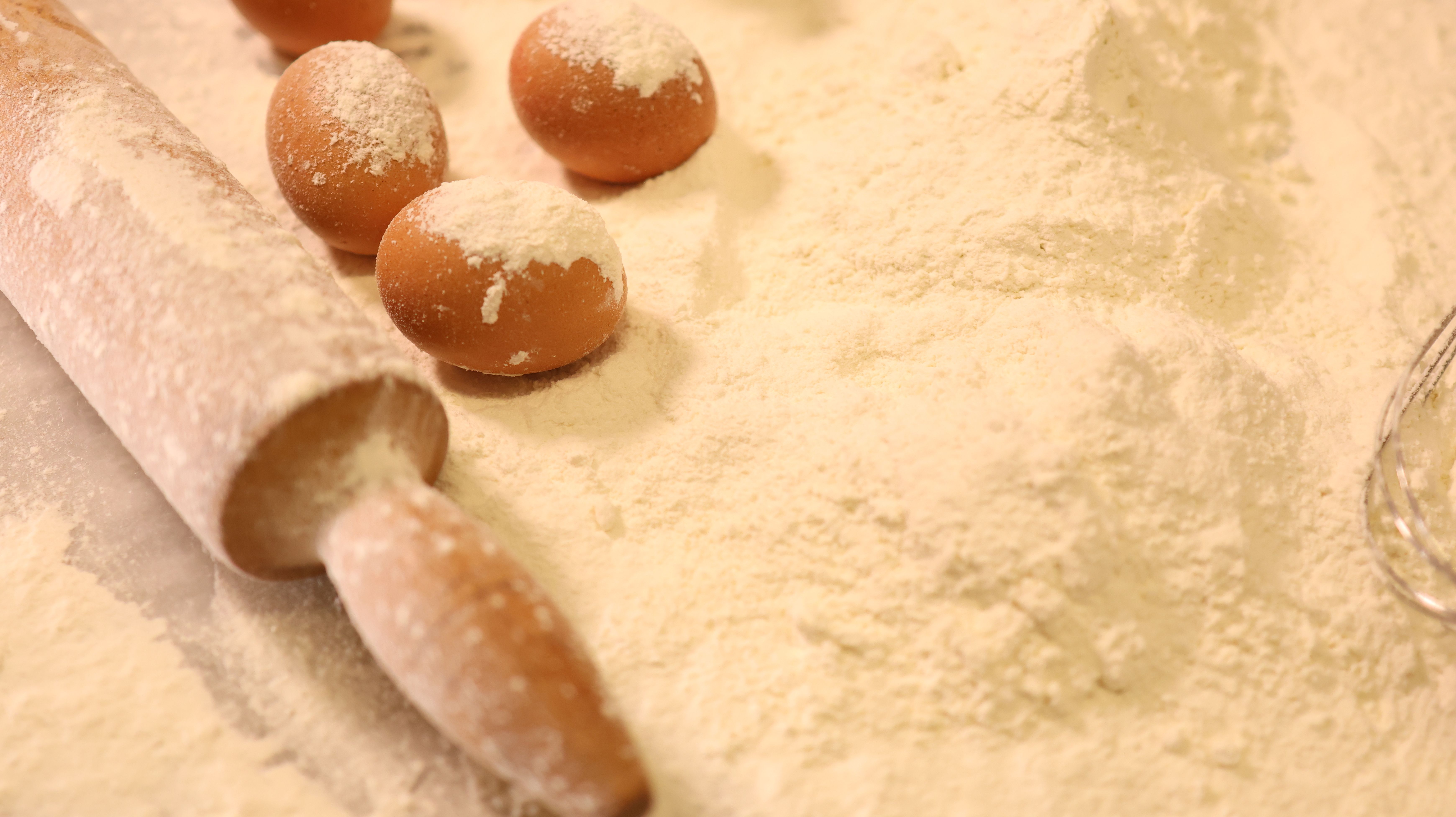 Baking ingredients, flour, and a rolling pin arranged on a work surface