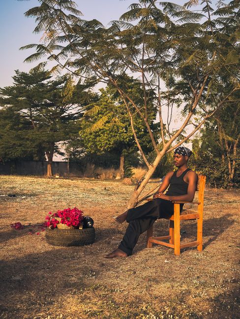 Man sitting under a tree in a serene outdoor setting, exuding calmness.