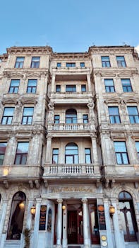 Grand historical hotel facade with classical architecture and ornate details under clear blue sky.